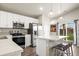 A modern kitchen featuring white cabinets and countertops, stainless steel appliances, and island with seating at 653 S Hoover Ave, Fort Lupton, CO 80621