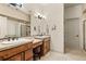 Bright bathroom with double vanities, wood cabinetry, and a glass-enclosed shower at 2714 Calmante Pl, Superior, CO 80027