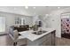 View of modern kitchen island with double sink and stainless dishwasher opening into a living room and stairway at 5121 N Yampa St, Denver, CO 80249