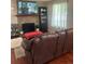 Cozy living room with a brick fireplace, TV, hardwood floors, and a comfortable brown leather couch at 8452 Everett Way # C, Arvada, CO 80005