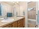 Bathroom with double sinks, wood cabinets, and a view into the tiled shower/tub combo at 16120 E 119Th Ave, Commerce City, CO 80022