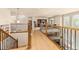 Upstairs hallway featuring hardwood floors, decorative railings, and views of the living area below at 16120 E 119Th Ave, Commerce City, CO 80022