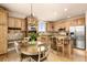 Open kitchen layout with wood cabinets, stainless steel appliances, and a cozy breakfast nook with a round table at 16120 E 119Th Ave, Commerce City, CO 80022