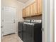 Functional laundry room with modern washer and dryer, overhead cabinets, and tiled flooring at 16120 E 119Th Ave, Commerce City, CO 80022