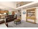 Open-concept living room with a leather sofa, natural light, and a view of the kitchen and upper level at 16120 E 119Th Ave, Commerce City, CO 80022