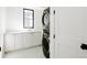 Well-lit laundry room with a stackable washer/dryer unit, white cabinetry, and a window for natural light at 3530 Fenton St, Wheat Ridge, CO 80212