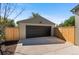 A detached garage with a black garage door and a concrete driveway, surrounded by a wooden fence at 949 Pontiac St, Denver, CO 80220
