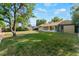 Spacious backyard featuring green grass, mature trees, sunroom, shed and wooden fence at 7310 Granada Rd, Denver, CO 80221