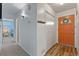 Hallway with orange front door and closet, leading to a bedroom with blue walls at 7310 Granada Rd, Denver, CO 80221