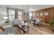 Cozy living room featuring a wood accent wall, hardwood floors, and ample natural light from large windows at 7310 Granada Rd, Denver, CO 80221