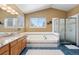 Bright bathroom with soaking tub, glass shower, tile accents, and dual mirrors over a single vanity at 12710 W 84Th Cir, Arvada, CO 80005