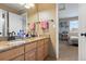 Well-lit bathroom with double sinks, granite countertops, and a view into the adjacent bedroom at 12710 W 84Th Cir, Arvada, CO 80005