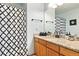 Bright bathroom featuring a vanity with a sink, a patterned shower curtain, and a large mirror at 12710 W 84Th Cir, Arvada, CO 80005