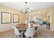 Dining room with wooden table, modern chairs, chandelier, and artwork; open to the living room at 12710 W 84Th Cir, Arvada, CO 80005
