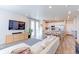 A modern open-concept living room and kitchen area with wood flooring and lots of natural light at 5156 Bittercress Rd, Brighton, CO 80640