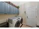 Functional laundry room with modern washer and dryer, storage cabinets, and access to the garage at 7056 S Owens St, Littleton, CO 80127