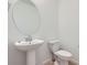 Elegant bathroom with a pedestal sink, oval mirror, modern toilet, and wood-look flooring at 2006 S Haleyville Way, Aurora, CO 80018