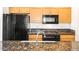 Full kitchen view with black appliances and granite countertops with wooden cabinets at 300 W 11Th Ave # 6G, Denver, CO 80204