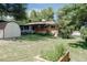 Expansive backyard with a lush lawn, garden beds, mature trees, and detached garage at 1475 S Urban Way, Lakewood, CO 80228