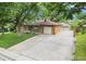 Brick home featuring a large concrete driveway and mature trees providing shade and curb appeal at 1475 S Urban Way, Lakewood, CO 80228