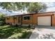 A charming brick home features a well-kept lawn, green shutters, and an attached garage at 1475 S Urban Way, Lakewood, CO 80228