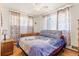A bright bedroom with hardwood floors, light streaming through patterned curtains, and a comfortable grey headboard at 1275 Otis St, Lakewood, CO 80214