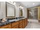 Bathroom featuring double sink vanity with black marble, shower, and golden hardware at 7330 Routt St, Arvada, CO 80005