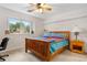 Neutral bedroom featuring a wooden framed bed, a large window, and a desk under the windowsill at 7330 Routt St, Arvada, CO 80005