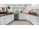 Bright kitchen has a stainless steel dishwasher, white cabinets, and a farmhouse-style sink at 7330 Routt St, Arvada, CO 80005