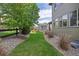 Scenic backyard with a grass pathway, privacy fence, mature trees, and manicured landscaping at 525 Grenville Cir, Erie, CO 80516