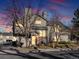 Evening view of a two story townhouse with lights on and landscaping at 9993 E Mexico Ave, Aurora, CO 80247