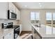Modern kitchen with stainless steel appliances, white cabinets, and island sink at 5718 Ranch St, Mead, CO 80504