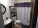 This is a bathroom with a toilet, cabinet sink, shelving unit, and black and white shower curtain at 9705 Canon Dr, Sedalia, CO 80135