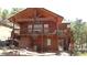 Unique cabin with a balcony, wooden details, and swing sets, set against a tree-lined backdrop at 9705 Canon Dr, Sedalia, CO 80135