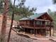 Exterior view of a two-story wood home surrounded by pine trees and native plants at 9705 Canon Dr, Sedalia, CO 80135
