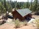 Exterior view of a wood-sided home and a detached garage, surrounded by pine trees at 9705 Canon Dr, Sedalia, CO 80135