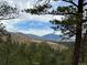 Expansive view of rolling mountains framed by lush trees against a blue sky at 9705 Canon Dr, Sedalia, CO 80135