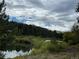 Scenic view of a serene pond surrounded by lush greenery and a backdrop of mountains at 9705 Canon Dr, Sedalia, CO 80135