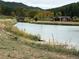 Views of the pond surrounded by grass and greenery, offering a serene waterfront atmosphere at 9705 Canon Dr, Sedalia, CO 80135