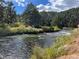 Serene flowing river surrounded by green foliage and mature trees on a sunny day at 9705 Canon Dr, Sedalia, CO 80135
