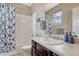 Well-lit bathroom featuring a vanity with a large mirror, bathtub with shower, and patterned shower curtain at 4883 S Sicily St, Aurora, CO 80015