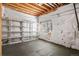 Unfinished basement with exposed wood beams and window with shelving along the far wall at 5421 Potentilla Ct, Parker, CO 80134