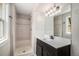 Updated bathroom with a walk-in shower, vanity with a dark wood cabinet, and a large mirror at 8727 E Girard Ave, Denver, CO 80231