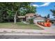 Traditional two-story home featuring a lush lawn, mature trees, and a charming blend of stone and siding exterior at 8727 E Girard Ave, Denver, CO 80231