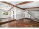 Open-concept living room featuring a vaulted ceiling, wood beam accents, hardwood floors, and a staircase nearby at 8727 E Girard Ave, Denver, CO 80231