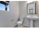 Well-lit half bathroom featuring a modern pedestal sink, contemporary fixtures, and a decorative mirror at 13398 E 99Th Pl, Commerce City, CO 80022