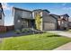 Two-story home with a lawn, two car garage, and newly planted tree at 13398 E 99Th Pl, Commerce City, CO 80022