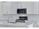 Modern kitchen featuring stainless steel appliances, white backsplash, and quartz countertops at 13398 E 99Th Pl, Commerce City, CO 80022