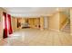 Large basement with tile floors, large red curtains, and staircase at 16650 E 107Th Ct, Commerce City, CO 80022