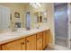 Bright bathroom featuring double sinks, wood cabinets, and a glass enclosed shower with marble tile at 16650 E 107Th Ct, Commerce City, CO 80022